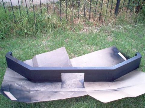 1988 Ford Bronco - A custom bumper is laid out on cardboard in the grass, possibly before installation.
