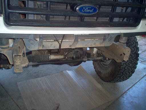 White Ford truck front frame and steering exposed with bumper removed