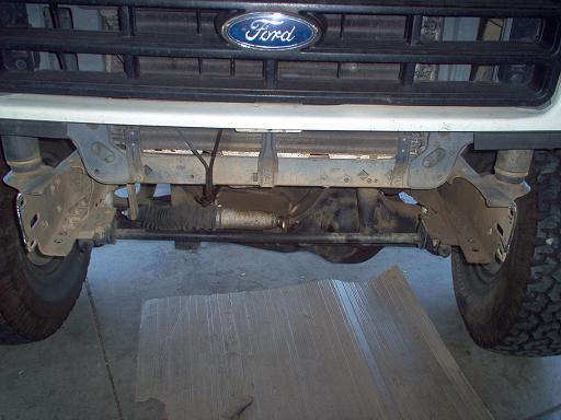 Front frame horns and steering exposed on white Ford truck with bumper removed