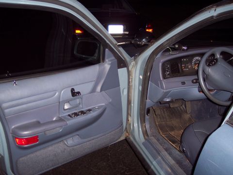 2001 Ford Crown Victoria - The interior of a 2001 Ford Crown Victoria is shown, with the driver's side door open, revealing the dashboard and seating area.