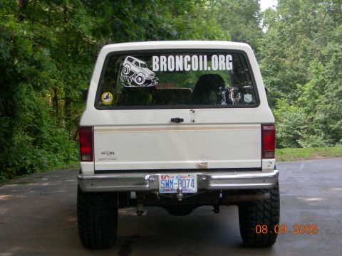 1984 Ford Bronco II - Rear view of a white Ford Bronco II with off-road tires and a website sticker on the rear window.