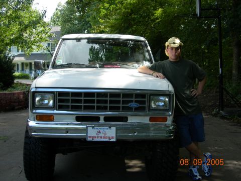 1984 Ford Bronco II - A white 1984 Ford Bronco II is shown from the front with a man standing beside it.