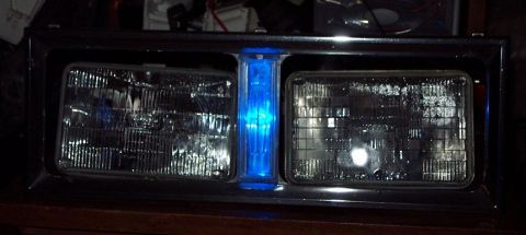 1985 Ford Crown Victoria LTD - This is a close-up of a vehicle's headlight assembly, a bright blue light in the center.