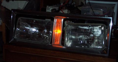 1985 Ford Crown Victoria LTD - A vehicle headlight assembly with chrome trim and an illuminated orange turn signal is shown.