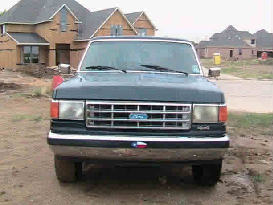 Front view of a dark blue Ford truck with a chrome grille and Texas flag emblem