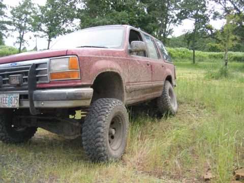 1991 Ford Explorer - Mud-covered 1991 Ford Explorer with aftermarket wheels and tires sits in a field.