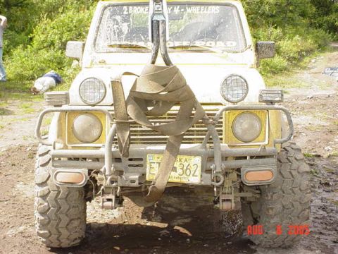 1987 Suzuki Samurai - This yellow off-road vehicle is equipped with a winch and a prominent strap across the front.