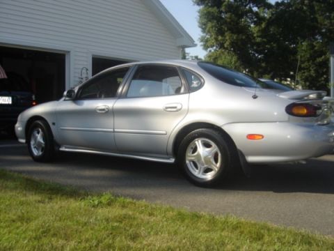 1999 Ford Taurus - This silver 1999 Ford Taurus sedan is shown from the rear quarter angle, parked in front of a garage.