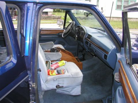 1995 Ford C-350 (Centurion Conversions) - Interior view of a blue vehicle, showing the dashboard, seats, and door panel with wood accents.