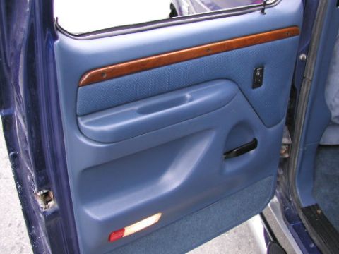 1995 Ford C-350 (Centurion Conversions) - Interior door panel of a 1995 Ford C-350 (Centurion Conversions) shows blue upholstery and wood accents.