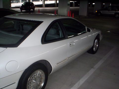 1994 Lincoln Mark VIII - A white coupe is parked in a dimly lit garage. Another vehicle is visible in the background.