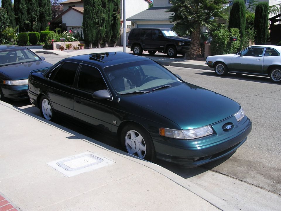 Dark green 1993 Ford Taurus sedan parked on a residential street, front 3/4 view