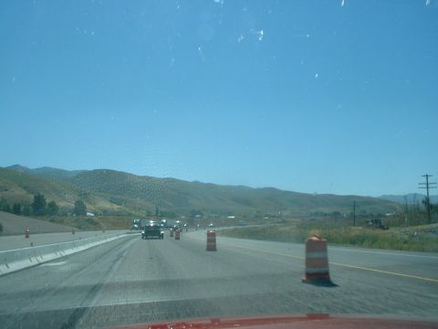 1999 Ford Crown Victoria - A highway scene shows traffic moving through a construction zone with orange barrels and mountains in the background.