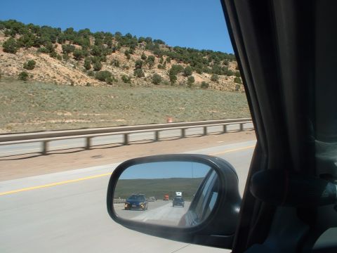 1999 Ford Crown Victoria - Driving on a highway with cars ahead, seen through the side mirror.