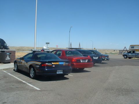 1999 Ford Crown Victoria - Several police vehicles are parked in a lot under a clear blue sky.