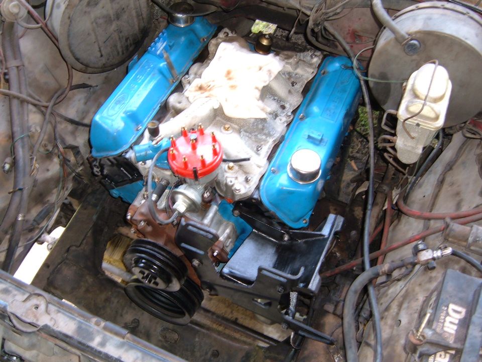 Engine bay with blue valve covers and red distributor cap. Wires and hoses are visible