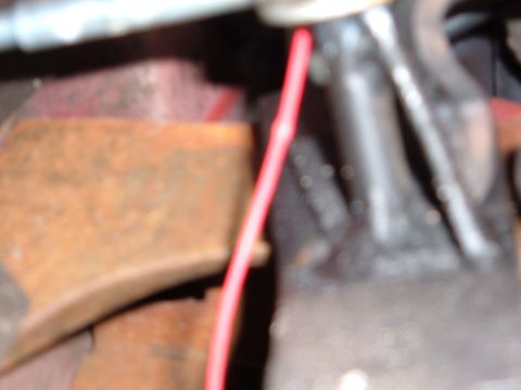 1978 Ford Bronco - A close-up view of engine components, including a red wire and rusty metal parts.