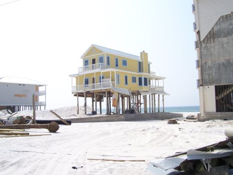 1995 Ford Bronco - Beach houses on stilts stand on a sandy shore, with debris scattered around.