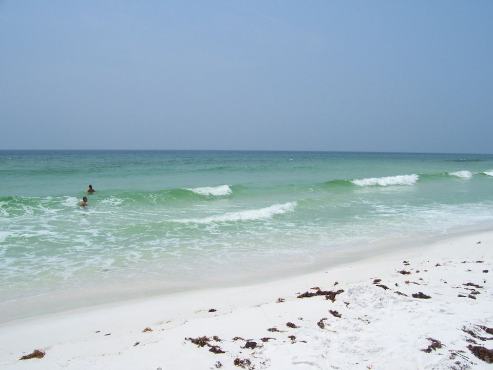 Beach scene with two swimmers in the ocean and white sand
