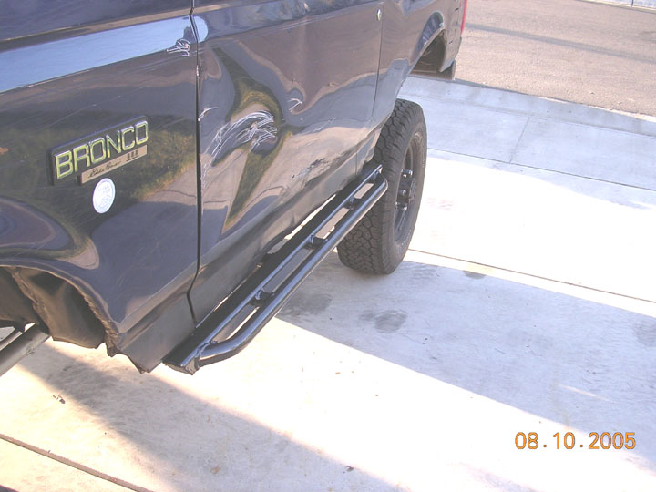 Dark Ford Bronco rear quarter with BRONCO badge and tubular rock sliders
