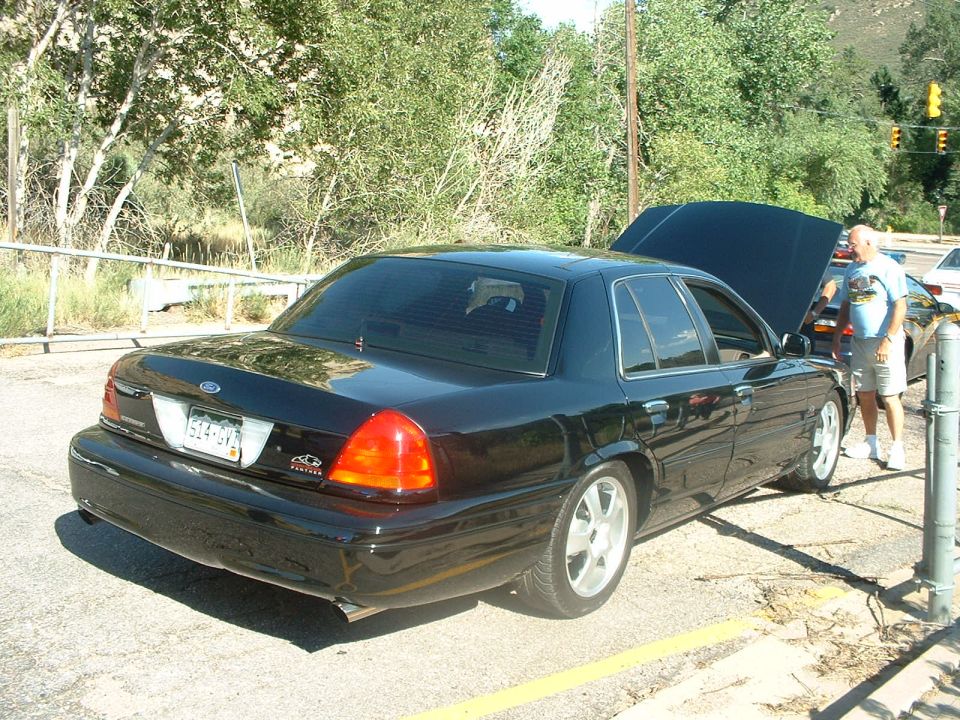 Black lowered Ford Crown Victoria rear three-quarter with hood open at car meet