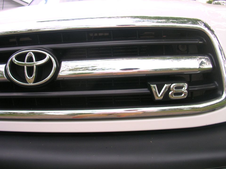 Close-up of a chrome Toyota grille with the Toyota emblem and V8 badge