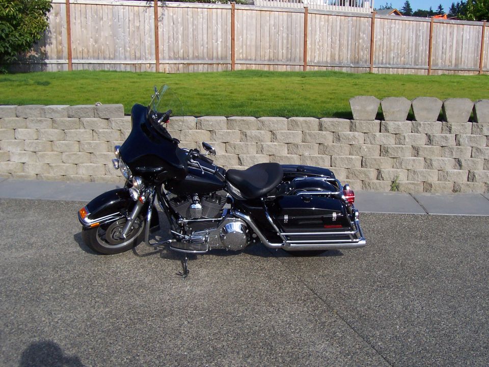 Black Harley-Davidson touring motorcycle with fairing and saddlebags on a driveway, side view