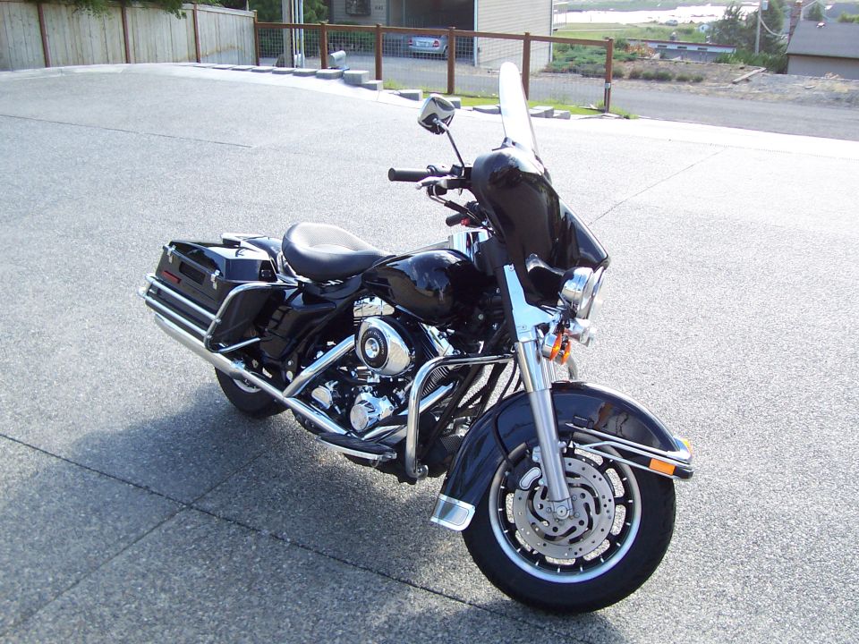 Black Harley touring motorcycle with tall windshield and dual exhaust on pavement