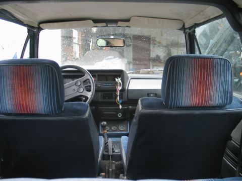 1986 Volkswagen Cabriolet - The interior of a car shows striped headrests and a dashboard with a radio.