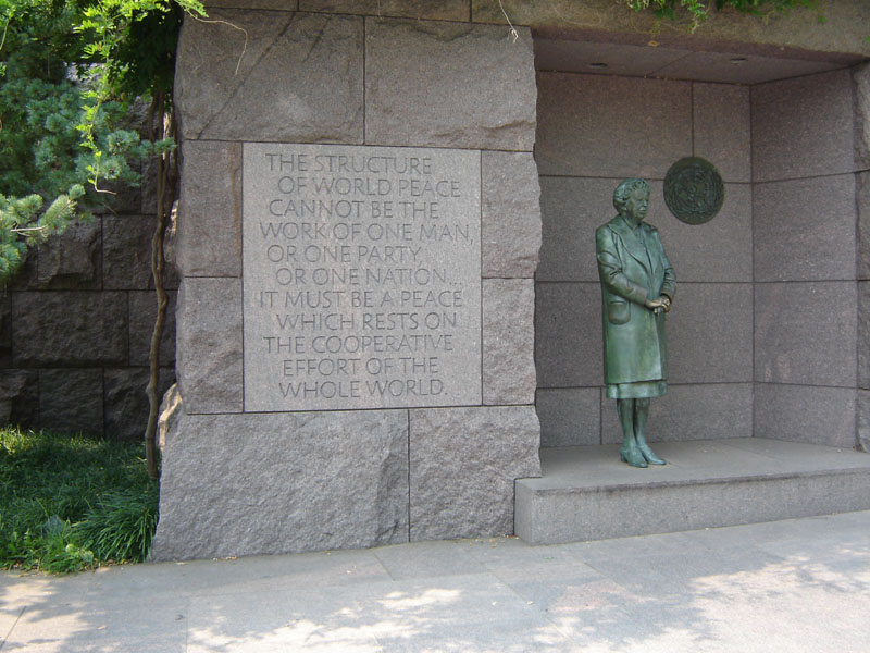Statue of Eleanor Roosevelt next to a stone wall with a quote about world peace