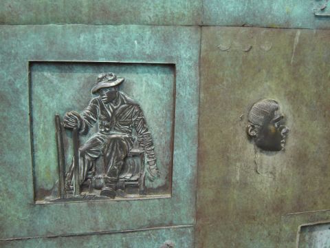 1986 Ford Bronco - Close-up of a bronze relief sculpture a seated figure and a profile.