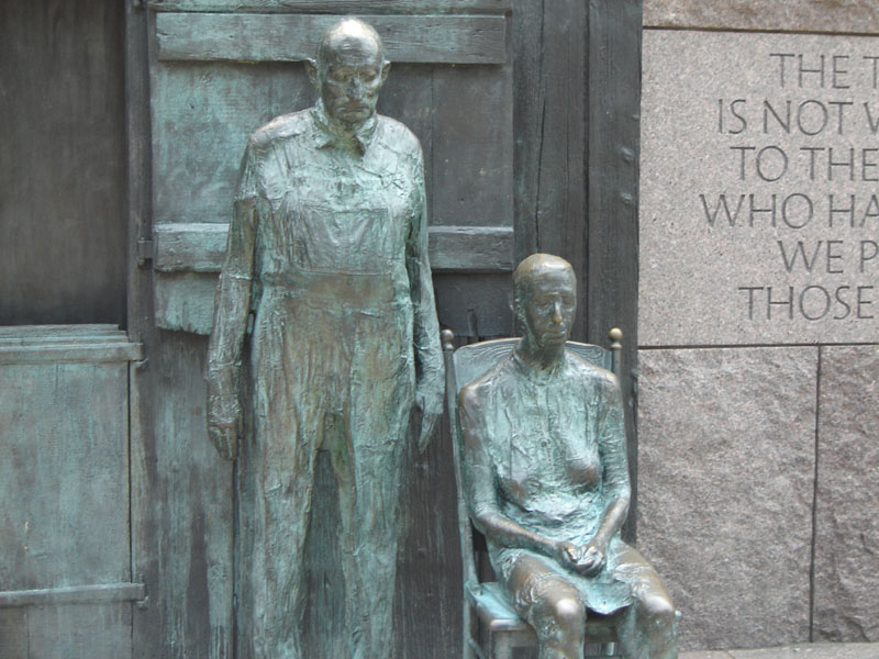 Bronze statues of a man and woman with engraved text on a stone wall
