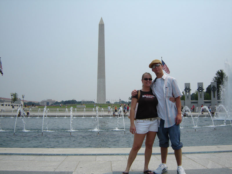 Couple posing in front of the Washington Monument with fountains