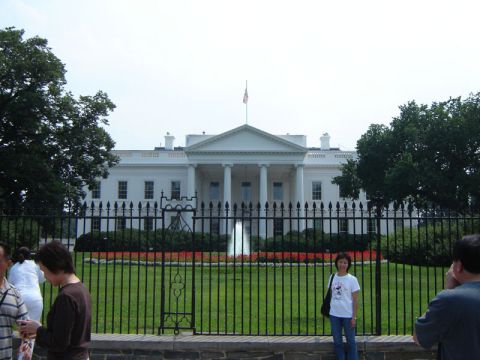 1986 Ford Bronco - The White House stands behind a fence with a fountain in the foreground and people observing.