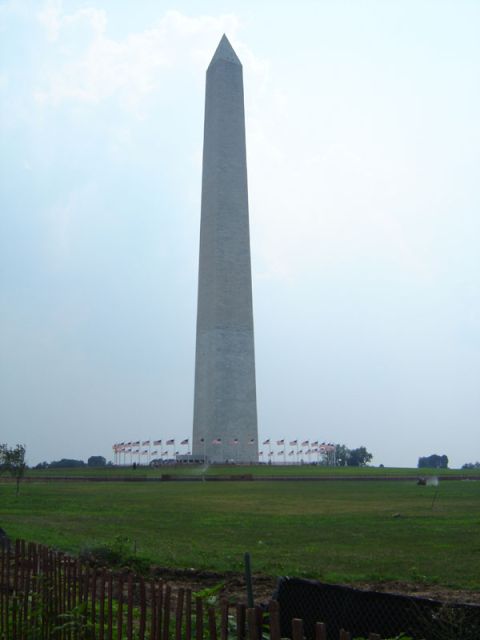 1986 Ford Bronco - The Washington Monument stands tall against a hazy sky, surrounded by flags and green space.