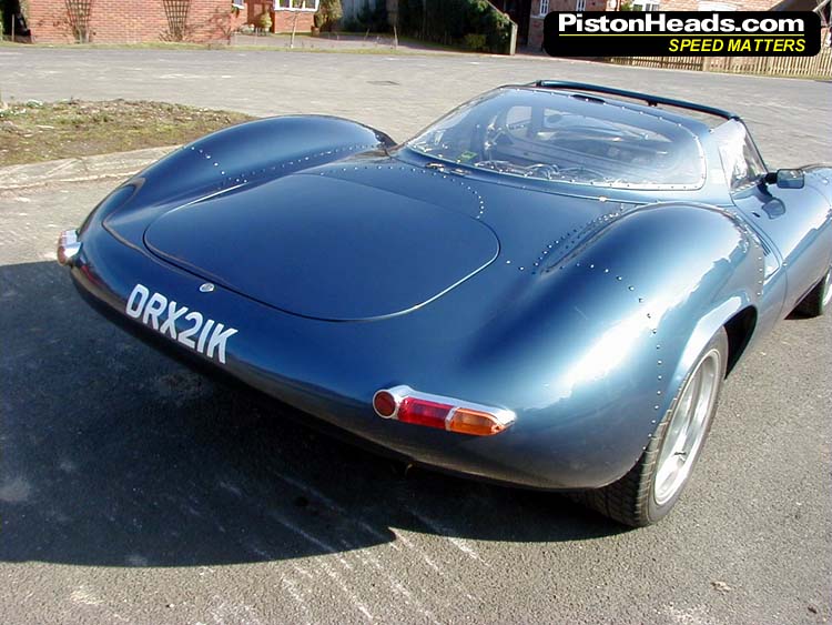 Blue sports car with riveted body panels and license plate DRX2IK, rear view