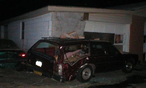 1987 Ford Crown Victoria LTD - A maroon station wagon with significant rear damage sits next to a building, with another vehicle partially visible.