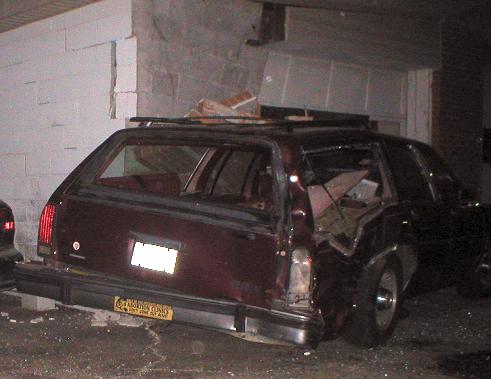 Station wagon rear end smashed into a brick wall, windows broken