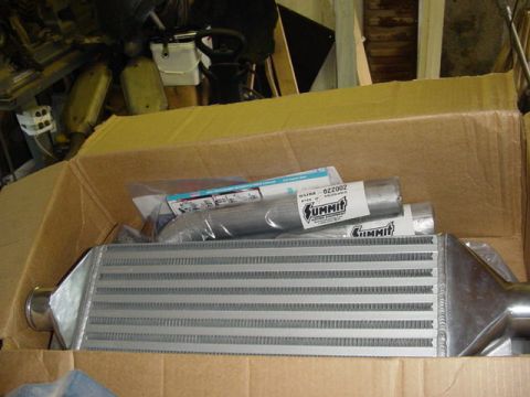 1995 Ford Mustang - An intercooler and exhaust pipe are shown inside a cardboard box, with Summit Racing branding visible on the packaging.