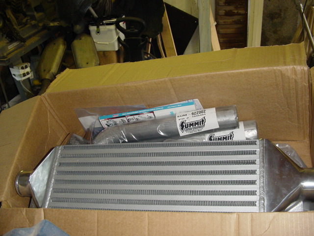 Intercooler and exhaust pipe with Summit Racing labels inside a cardboard box