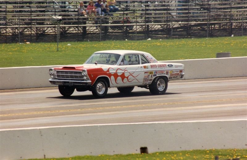 White drag racing coupe with red flames launching on a drag strip