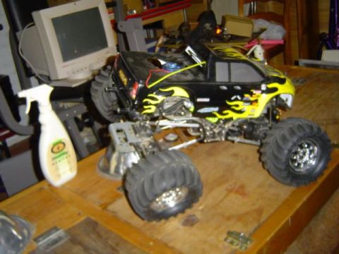 1979 Ford Bronco - A remote control monster truck with flame decals sits on a wooden surface next to a spray bottle and a computer monitor.