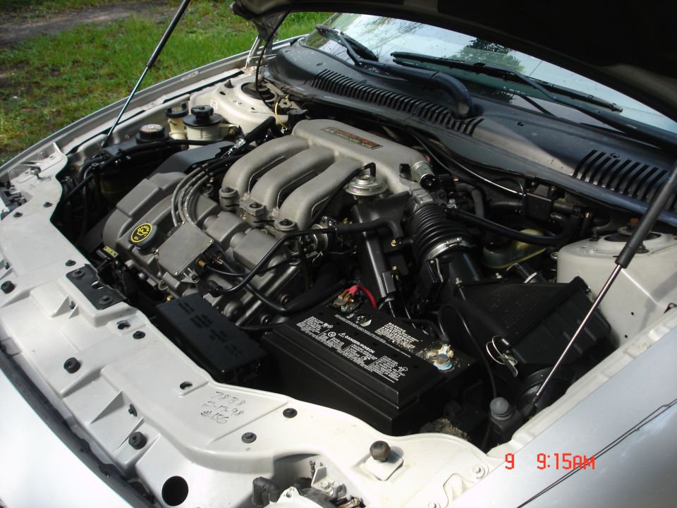 Silver 1998 Ford Taurus engine bay, V6 engine, battery, and air intake visible