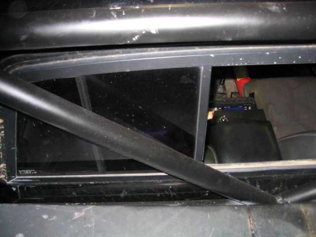 Roll cage inside a vehicle, looking through the rear window at some equipment
