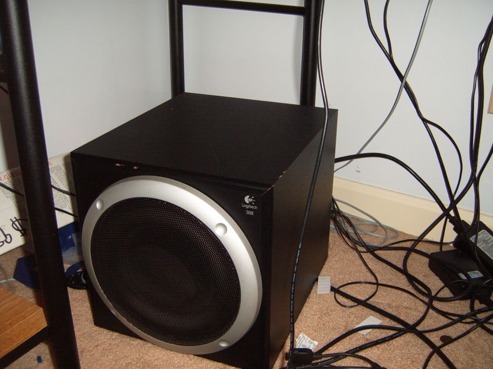 Logitech 301 subwoofer with silver trim and black grille, next to cables and a desk leg