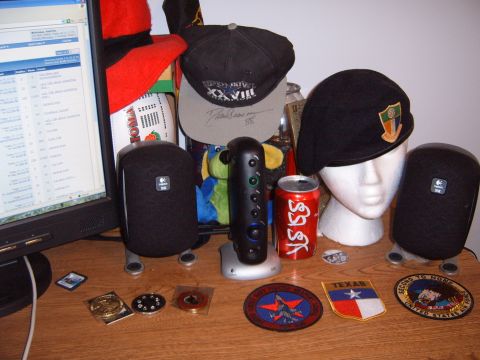 1988 Ford Bronco - A desk setup includes a computer monitor, speakers, hats, and various collectible items.