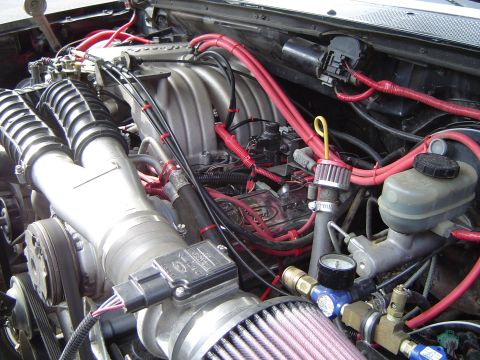 1989 Ford Bronco - Close-up of an engine bay showing modifications to the air intake and fuel system.