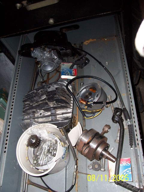 1987 Ford Bronco - Various motorcycle engine components are organized in a storage unit, including a cylinder, crankshaft, and carburetor.
