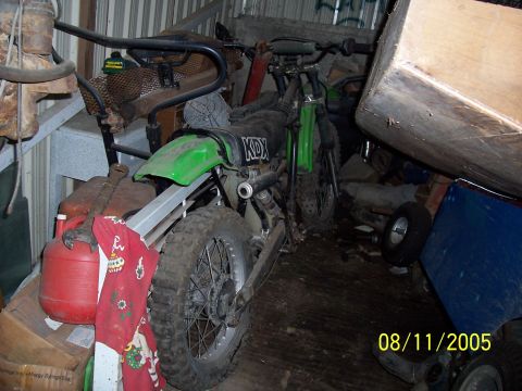 1987 Ford Bronco - A green dirt bike with KDX markings is stored indoors amongst various items.