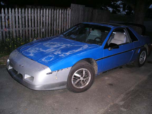 Blue 1984 Pontiac Fiero with a silver front bumper and faded paint on the hood